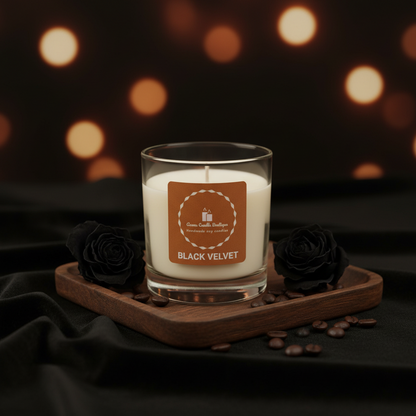 Candle labeled 'Black Velvet' on a wooden tray with black roses and coffee beans, blurred lights in the background.