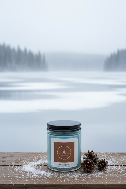 Candle with a label on a wooden surface in front of a snowy landscape