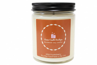 Candle jar with a black lid and orange label on a white background